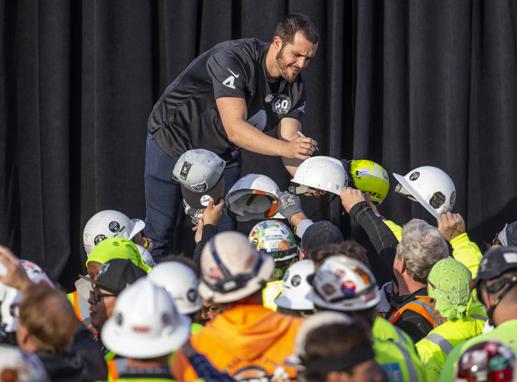 Las Vegas Raiders quarterback Derek Carr, center, signs autographs for construction worker duri ...