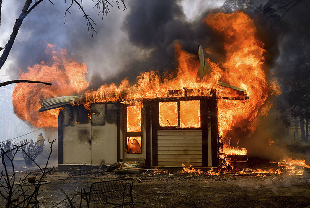 Flames from the Morton Fire consume a home near Bundanoon, New South Wales, Australia, on Thurs ...