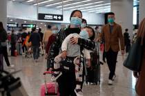 Passengers wearing protective face masks enter the departure hall of a high speed train station ...