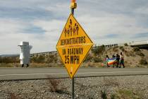 Anti-nuclear demonstrators, some in costume, pass by a sign that warns motorists of their prese ...