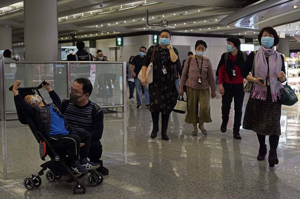 Passengers wear masks as they walk at the Hong Kong International Airport in Hong Kong Saturday ...