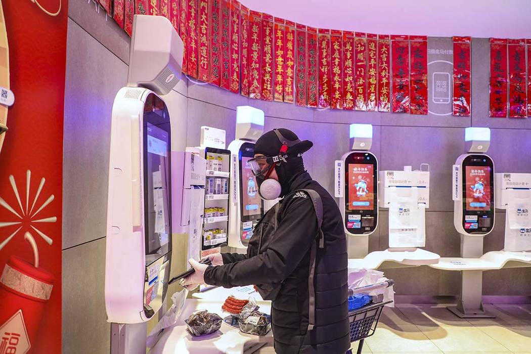 A shopper wearing goggles, a face mask and gloves uses a self checkout machine at a supermarket ...