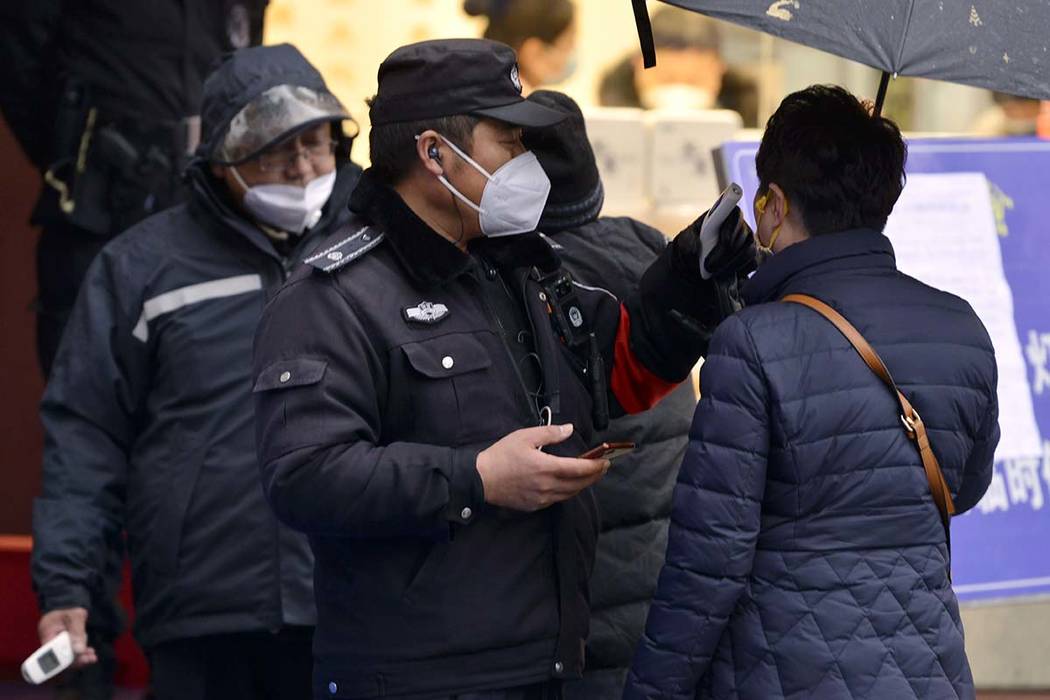 A policeman wearing a face mask takes a tourist's temperature at the Qinhuai scenic zone in Nan ...