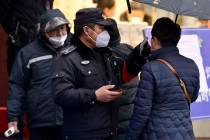 A policeman wearing a face mask takes a tourist's temperature at the Qinhuai scenic zone in Nan ...