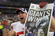 New York Giants linebacker Zak DeOssie holds up a newspaper after the Giants beat the New Engla ...