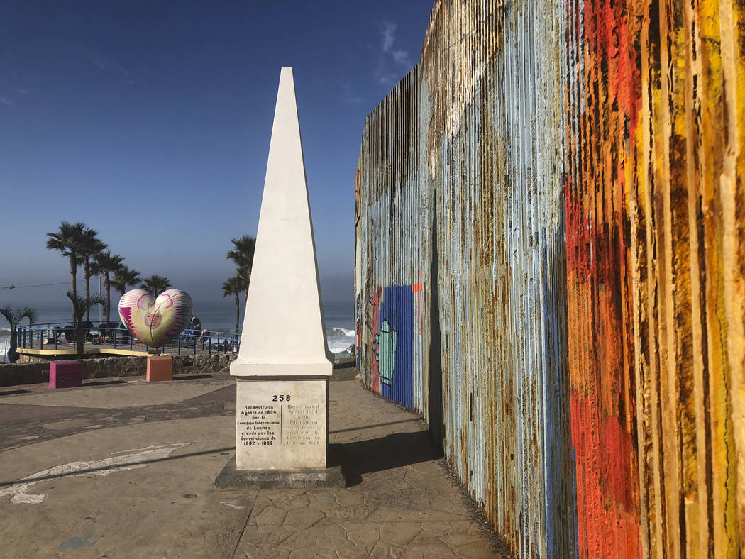 A white obelisk located on the Mexican side of a border marks the official international line b ...