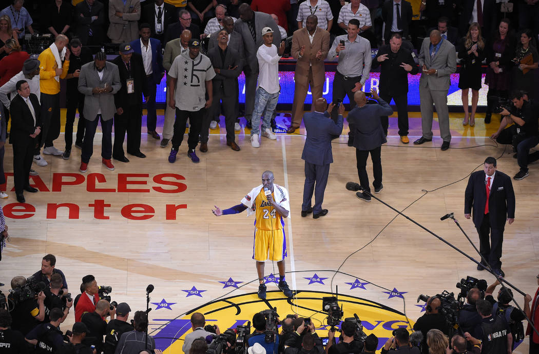 Los Angeles Lakers forward Kobe Bryant speaks to fans as friends and former teammates stand beh ...