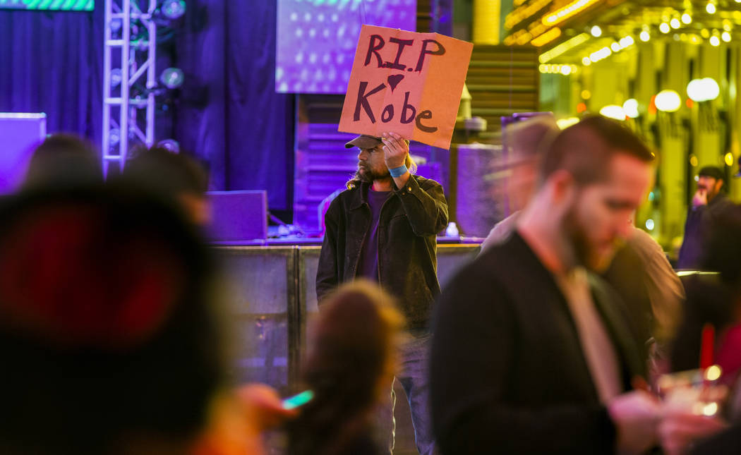 Aaron Young holds up a sign at the Fremont Street Experience as a memorial to Kobe Bryant follo ...