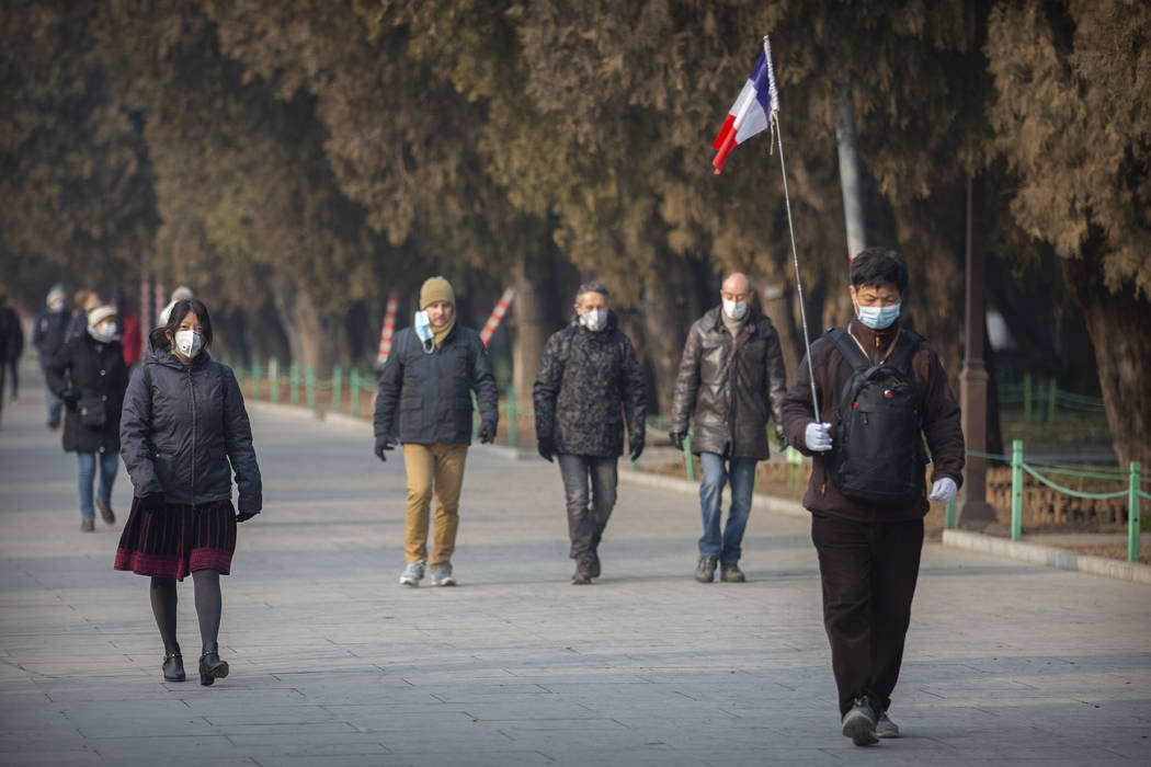 Members of a foreign tour group wear face masks as they walk in a park near the closed Forbidde ...