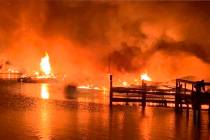 A fire burns on a dock where at least 35 vessels, many of them houseboats, were destroyed by fi ...