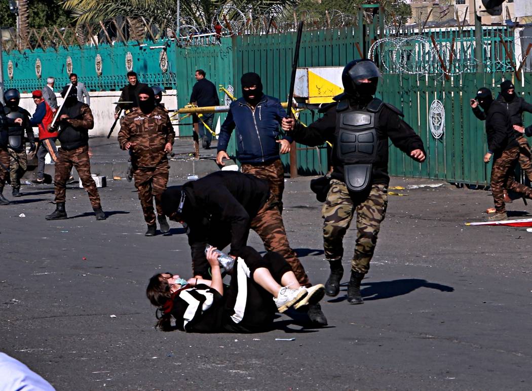 A riot policeman pins down a female anti-government protester to search her while security forc ...