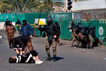 A riot policeman pins down a female anti-government protester to search her while security forc ...