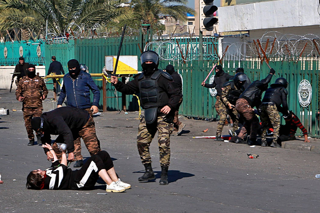 A riot policeman pins down a female anti-government protester to search her while security forc ...