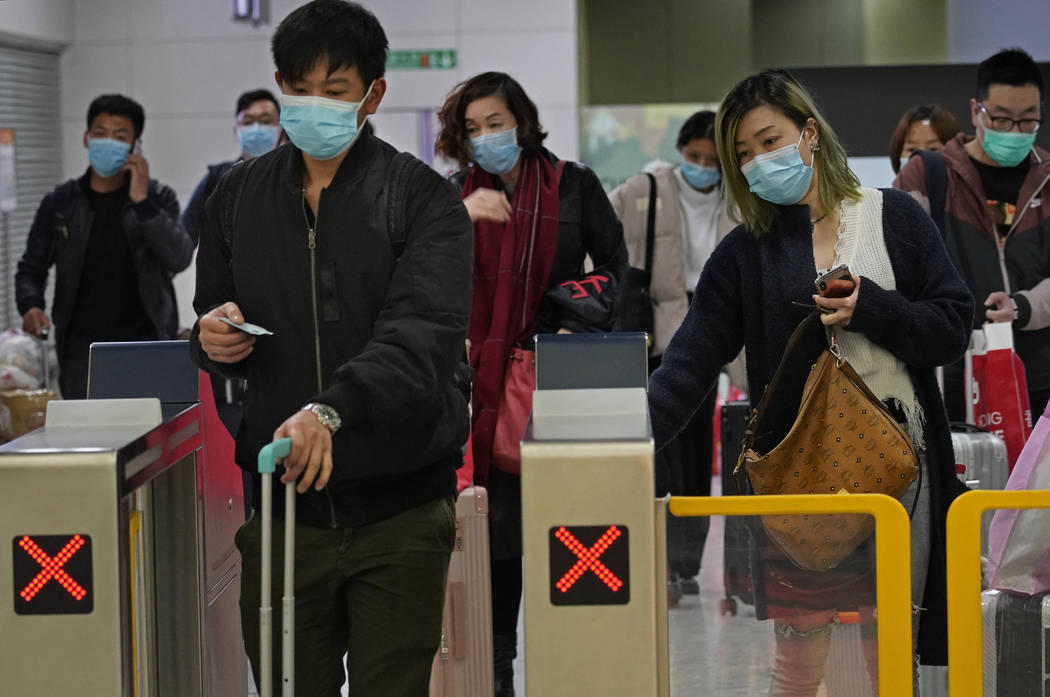 Passengers wear protective face masks arrive at the high speed train station in Hong Kong, Tues ...