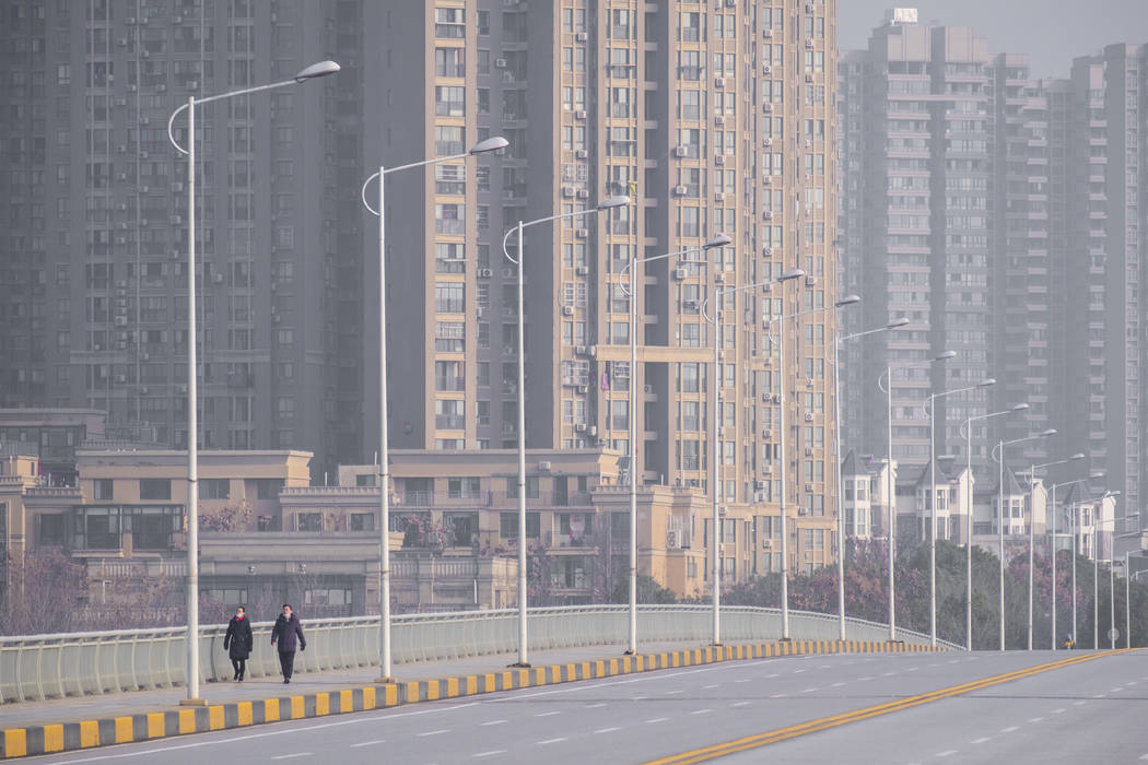 People wearing face masks walk down a deserted street in Wuhan in central China's Hubei Provinc ...