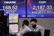 A currency trader wearing a mask watches a calendar at the foreign exchange dealing room of the ...