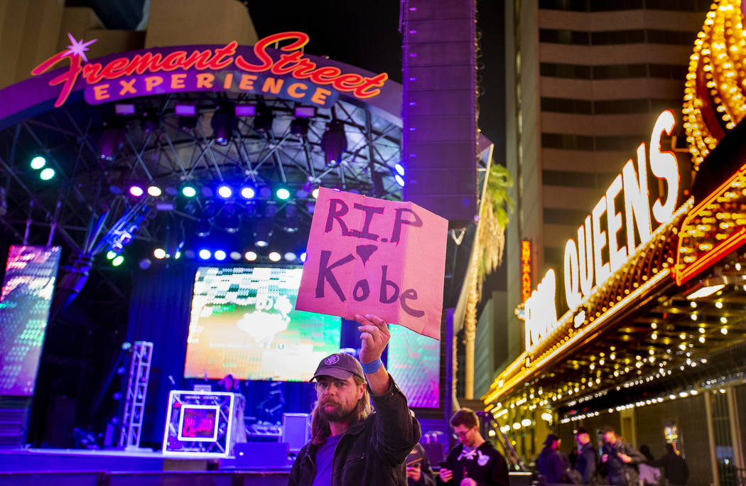 Aaron Young holds up a sign at the Fremont Street Experience as a memorial to Kobe Bryant follo ...