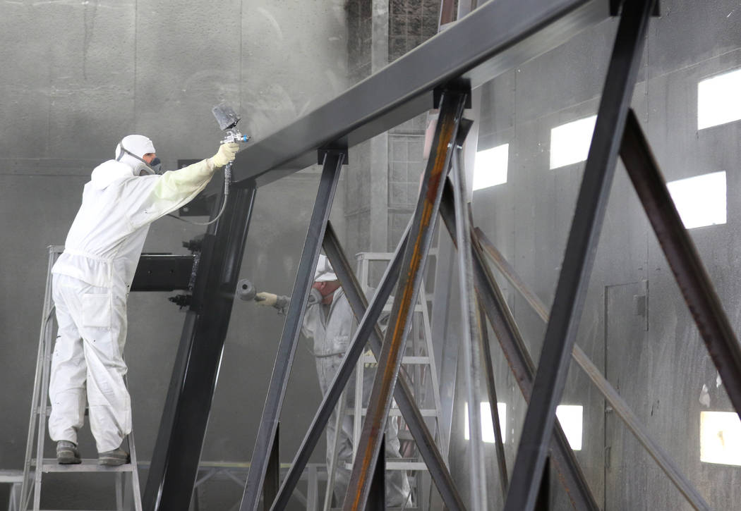 Theron Day, left, and Frank Brown spray paint signage beams for the new Allegiant Stadium signa ...