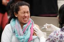 Ana Farfan reacts to getting an influenza vaccine shot at Eastfield College in Mesquite, Texas, ...