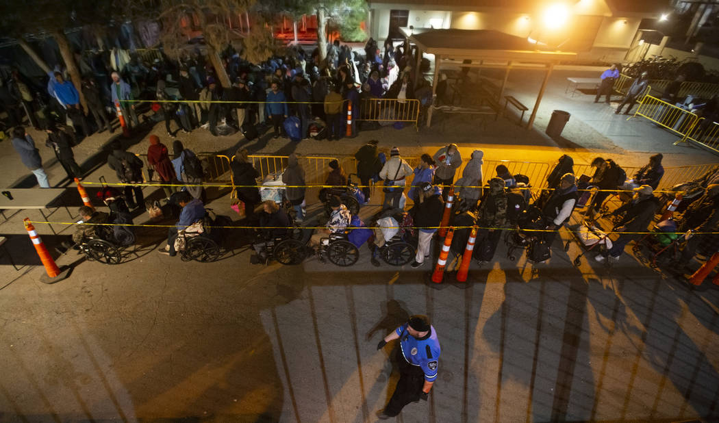 People wait in line to check in and get a sleeping mat at the Courtyard Homeless Resource Cente ...