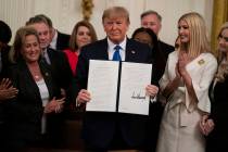 President Donald Trump shows off an executive order to help combat human trafficking in the Eas ...