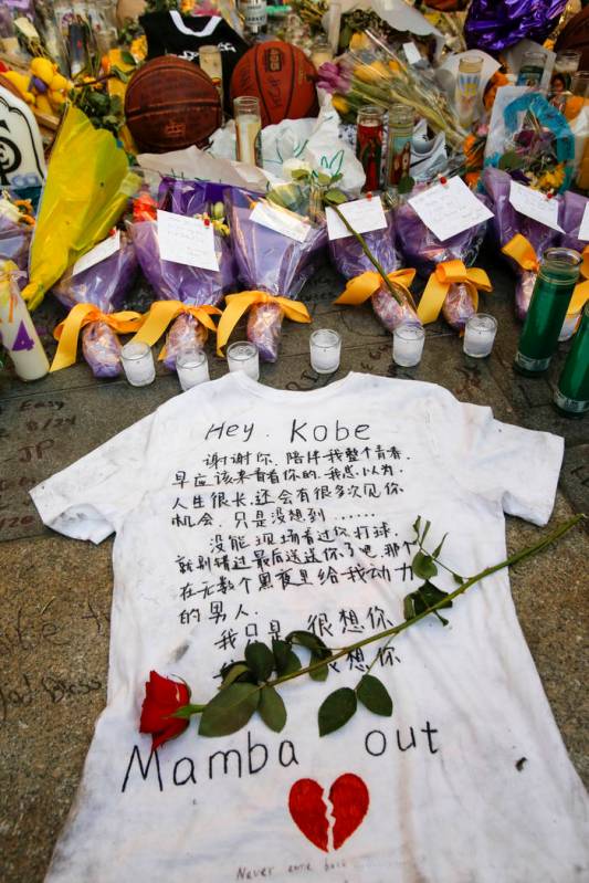 Flowers, basketballs, sweat shirts, candles and message notes are placed at a memorial for the ...