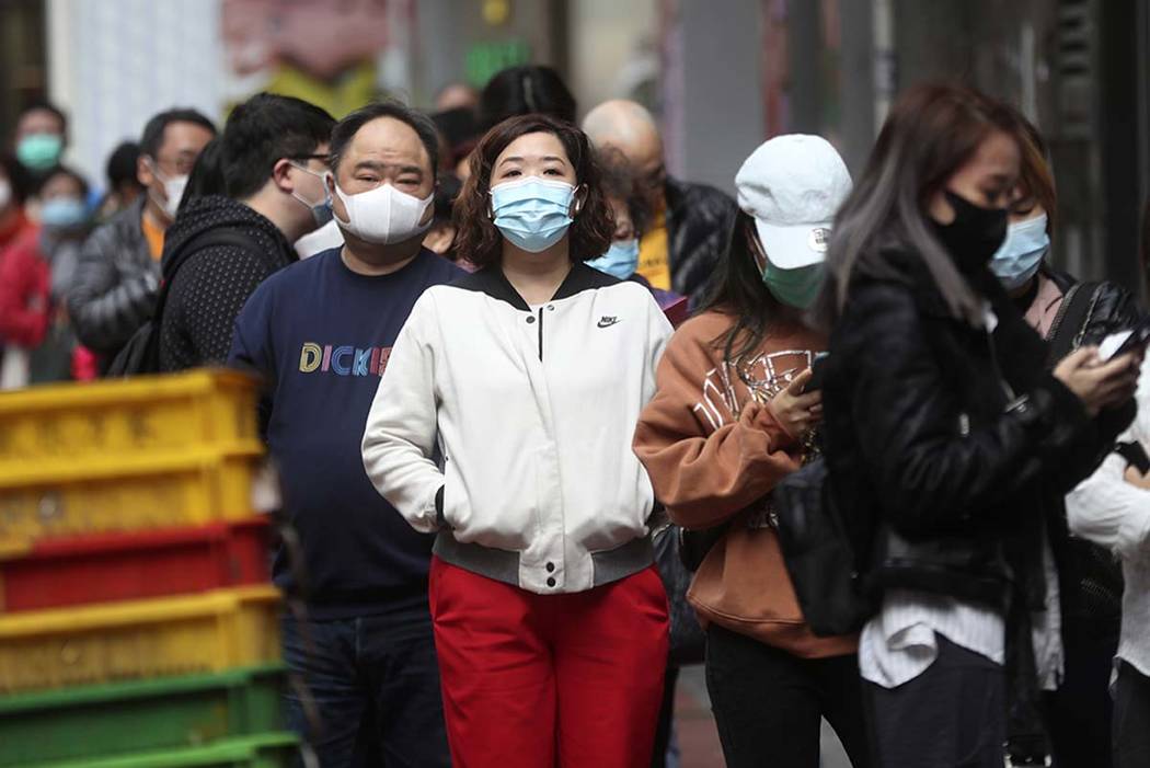 People queue up to buy face masks at a cosmetics shop in Hong Kong, Saturday, Feb, 1, 2020. Chi ...