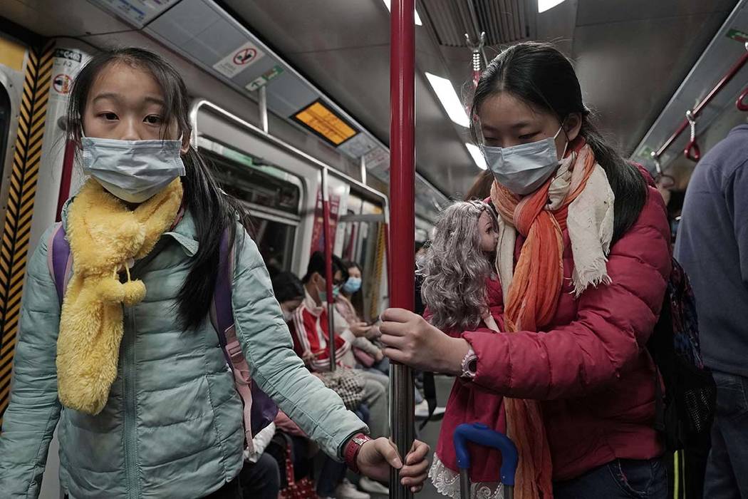Two girls with face masks ride the subway in Hong Kong, Saturday, Feb, 1, 2020. China’s ...