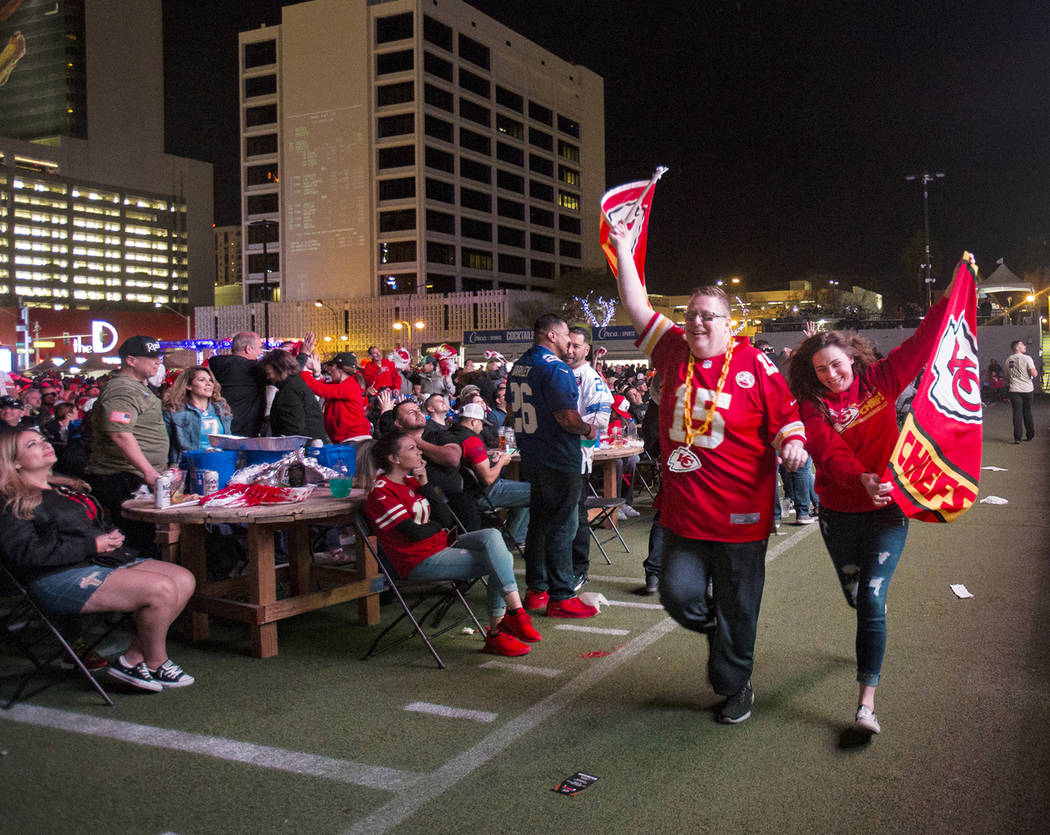 Steven Foster and Jane Fry, both of Kansas City, run a Kansas City Chiefs flag in front of the ...
