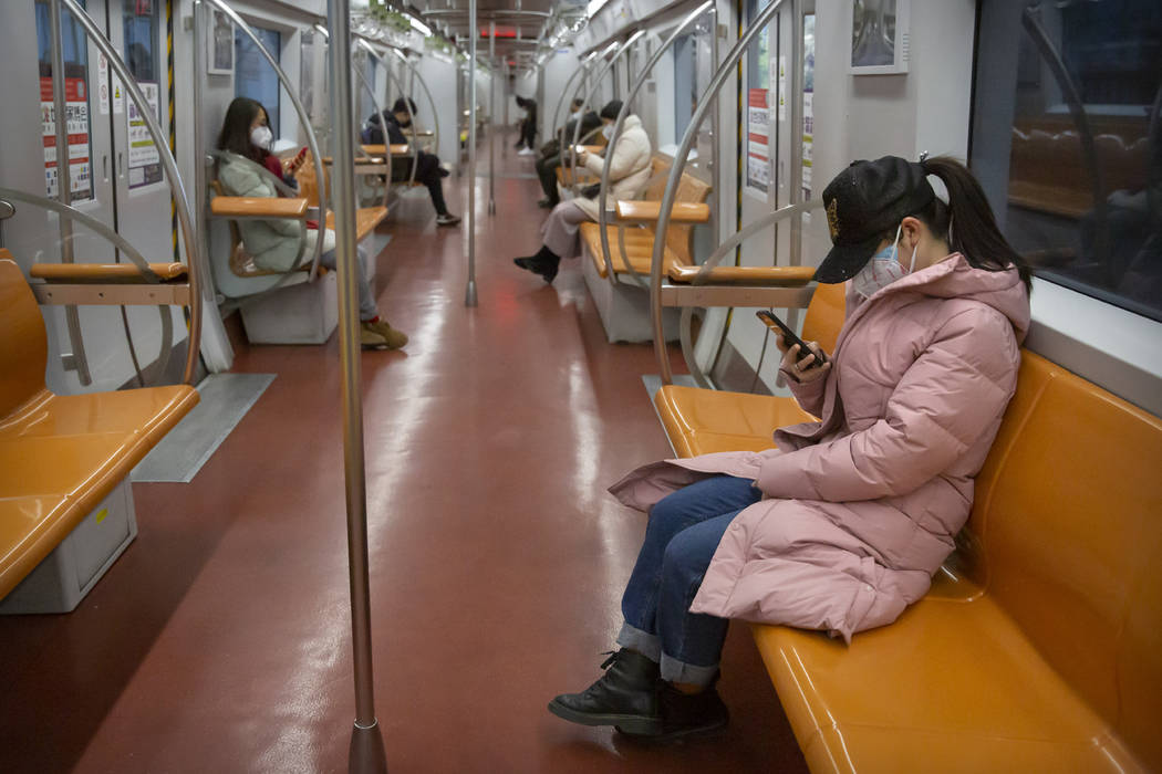 People wearing face masks ride a mostly empty subway train during the morning rush hour in Beij ...