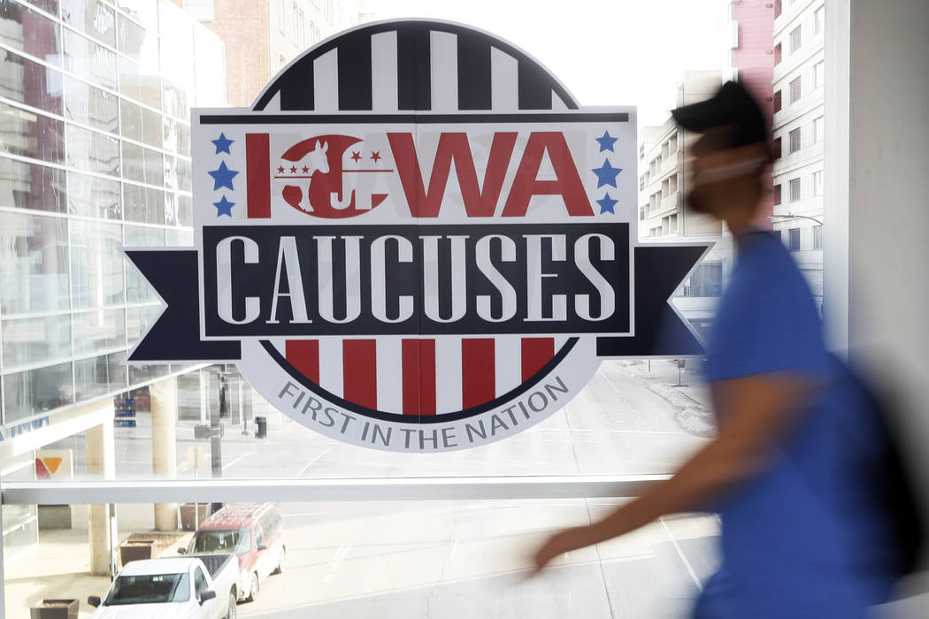A pedestrian walks past a sign for the Iowa Caucuses on a downtown skywalk, Tuesday, Feb. 4, 20 ...