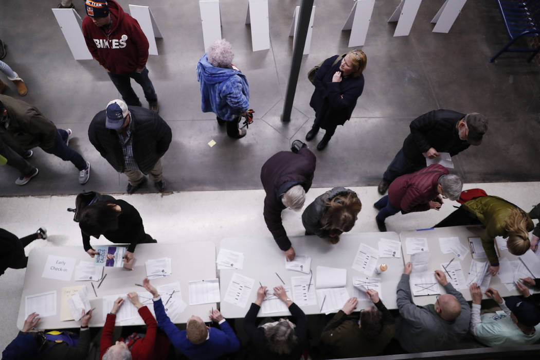 Caucus goers check in at a caucus at Roosevelt High School, Monday, Feb. 3, 2020, in Des Moines ...