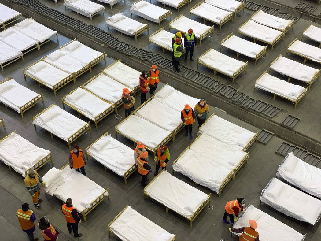 Workers arrange beds in a convention center that has been converted into a temporary hospital i ...