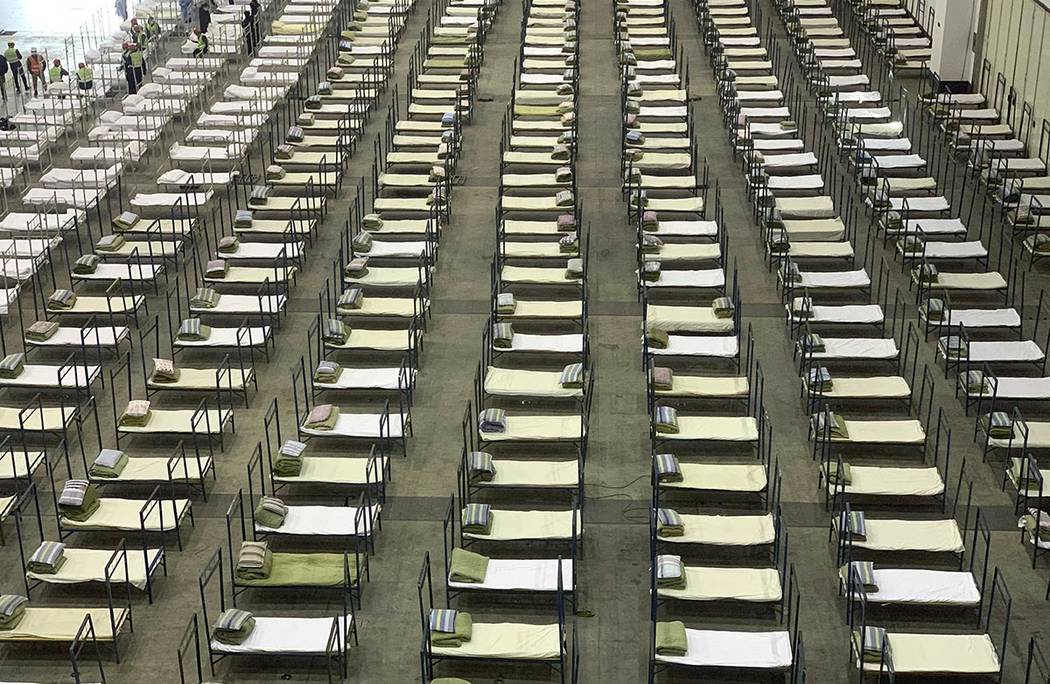 Workers arrange beds in a convention center that has been converted into a temporary hospital i ...