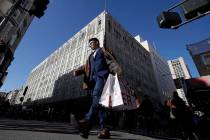 In this Nov. 29, 2019, file photo, man carries shopping bags across the street from a Macy's st ...