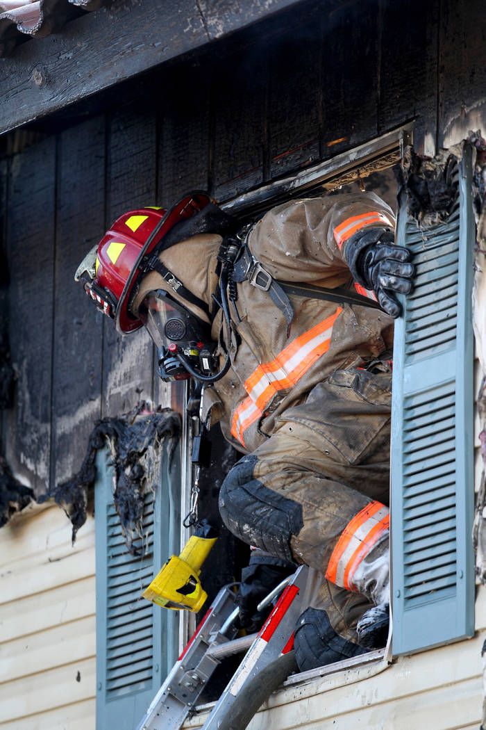 A firefighter exits a second floor window while working a blaze at Lantana Apartments on Charle ...