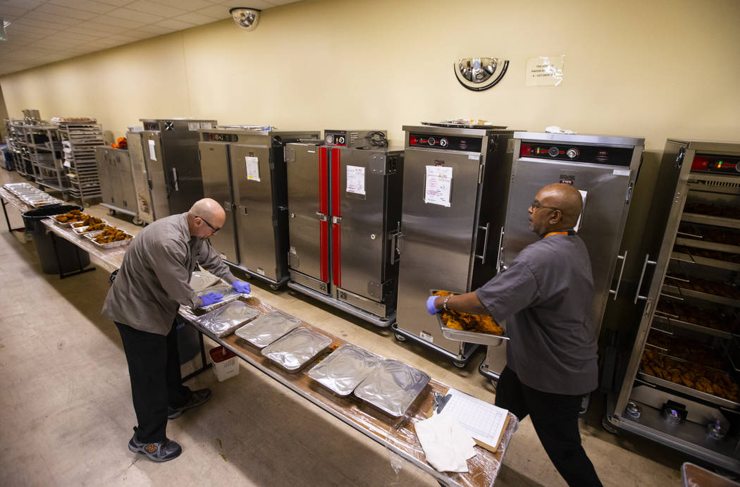 Bob Ayouba, left, and Sarif El-Amin, of Three Square food bank, package fried chicken and other ...