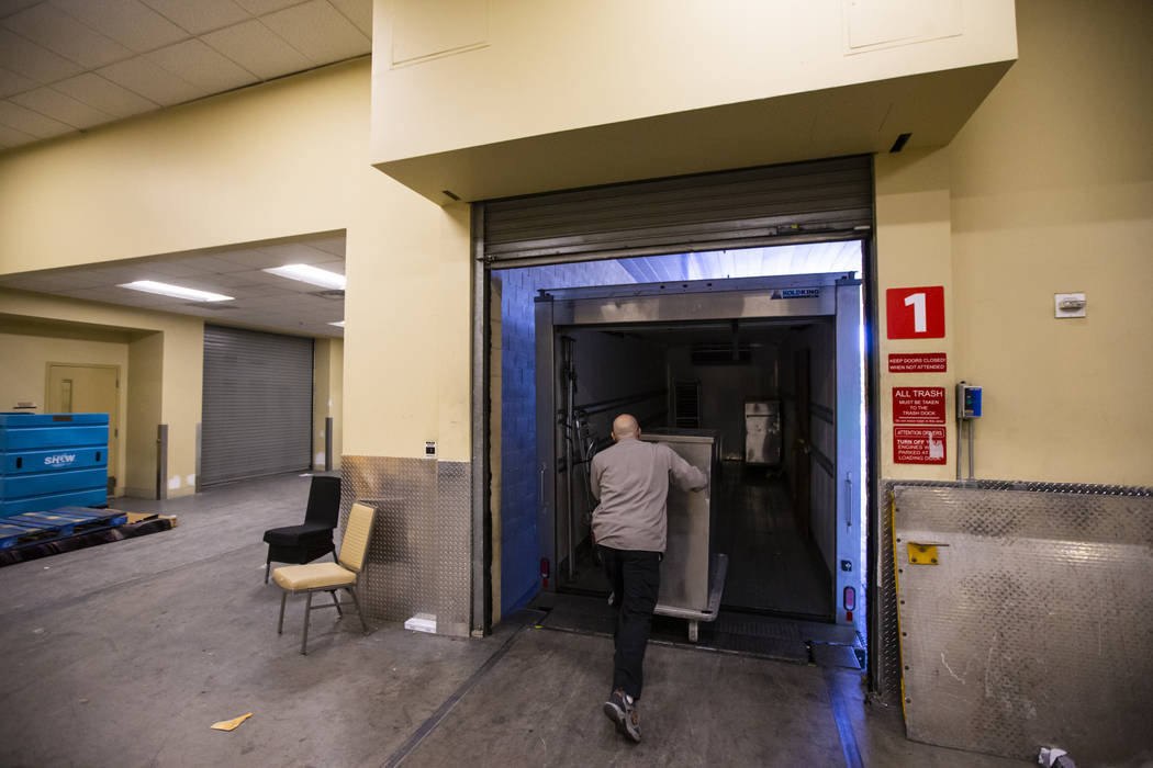 Bob Ayouba, of Three Square food bank, moves the donated surplus banquet food from Aria into a ...