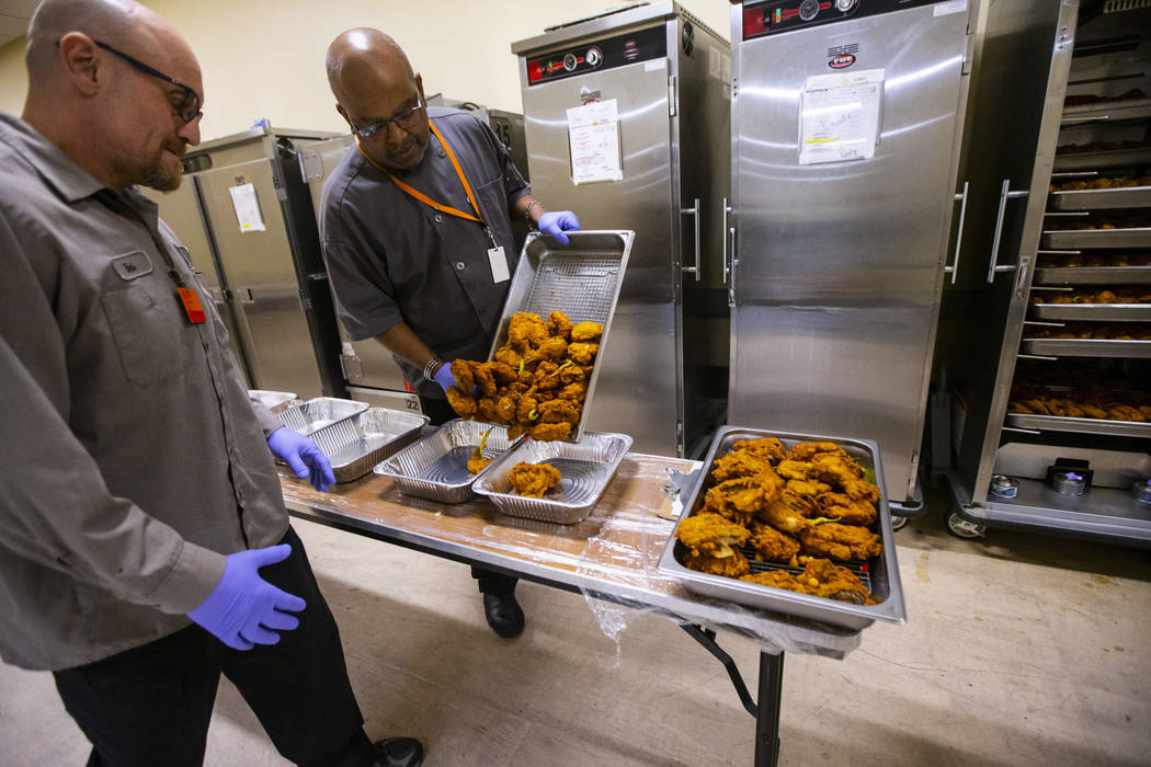Bob Ayouba, left, and Sarif El-Amin, of Three Square food bank, package fried chicken and other ...