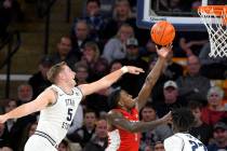 UNLV guard Amauri Hardy (3) shoots as Utah State guard Sam Merrill (5) and center Neemias Queta ...