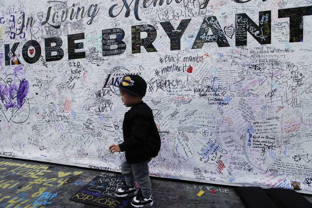 A boy walks by a standing board with messages for the late Kobe Bryant at a memorial for Bryant ...