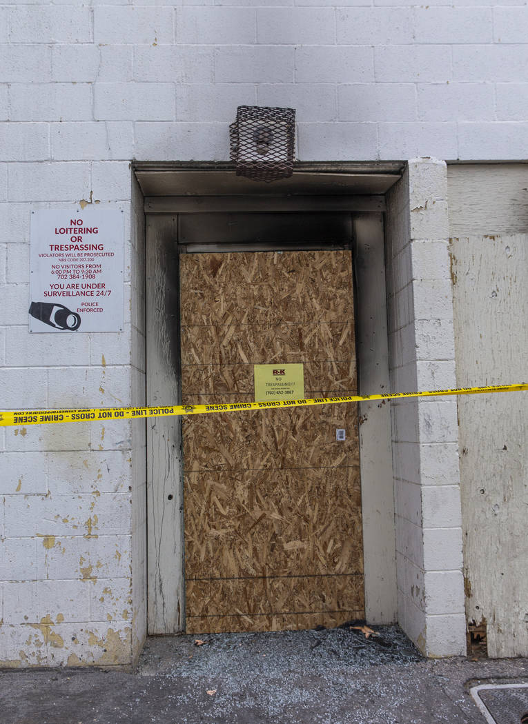 The broken rear glass door of the Alpine Motel Apartments is boarded up and lined with crime ta ...