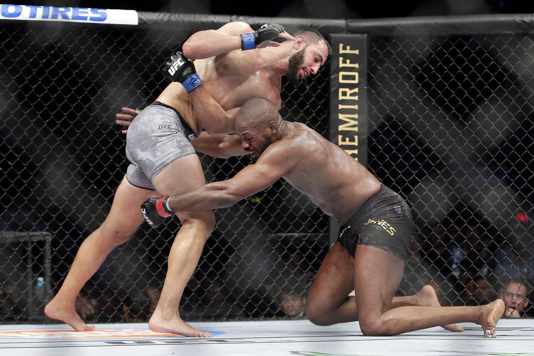 Jon Jones, right, goes for a take down of Dominick Reyes, left, during a light heavyweight mixe ...