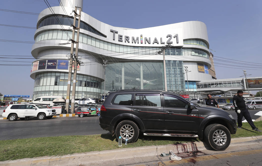 Thai rescue teams walk pass a shooting victim's vehicle outside Terminal 21 Korat mall in Nakho ...