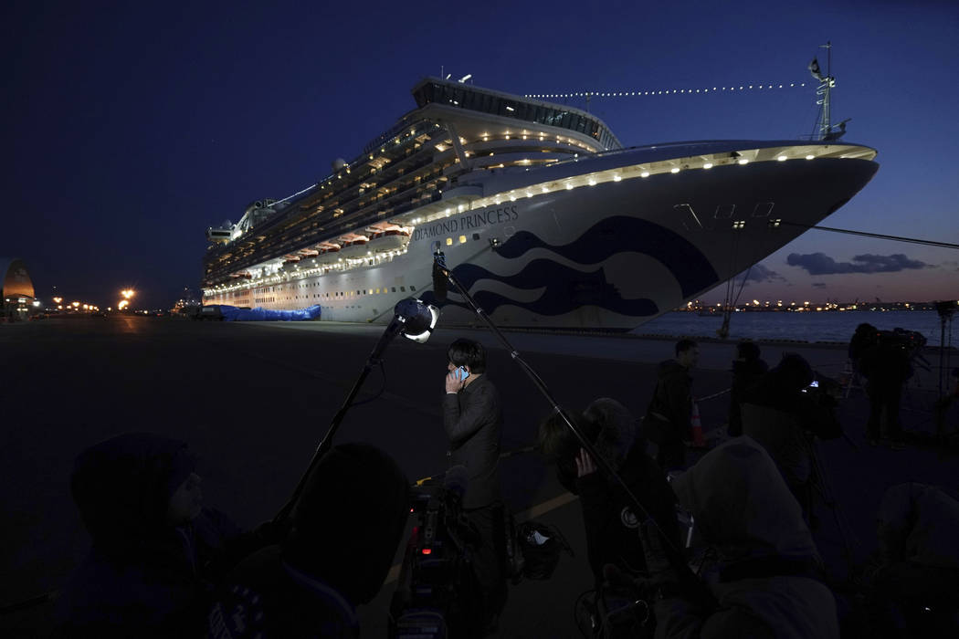 Journalists work near the quarantined Diamond Princess cruise ship sitting at the Yokohama Port ...