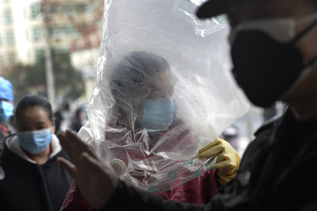 A man wearing a protective face mask covered himself with a plastic cover before enters a super ...
