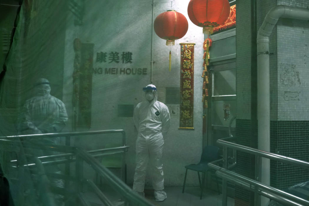 Personnels wearing protective suits wait near an entrance at the Cheung Hong Estate, a public h ...