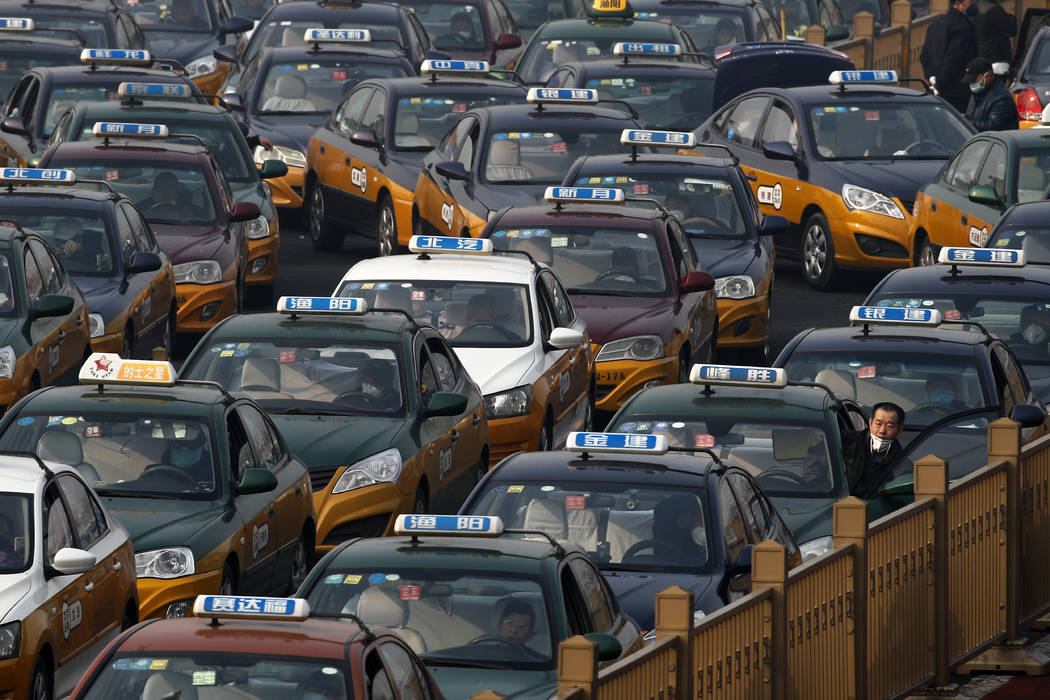 A taxi driver looks out from his car as they pile up to wait for customers at the train station ...
