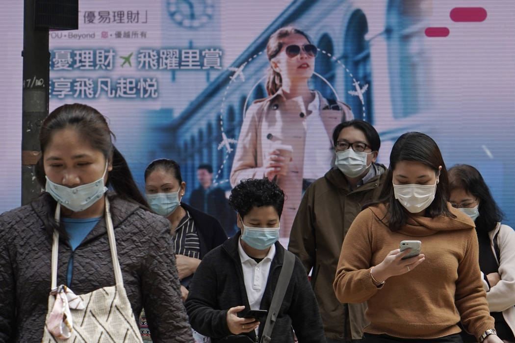 People wearing protective face masks walk on a street in the Central, the business district of ...