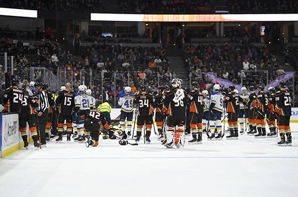 Members of the St. Louis Blues and Anaheim Ducks gather on the ice as Blues defenseman Jay Bouw ...